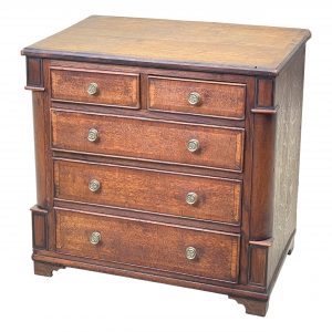 A Very Attractive George III Period Oak Childs Chest Having Well Figured And Crossbanded Top Above Two Short And Three Long Drawers Flanked By Curved Corners Raised On Replaced Bracket Feet